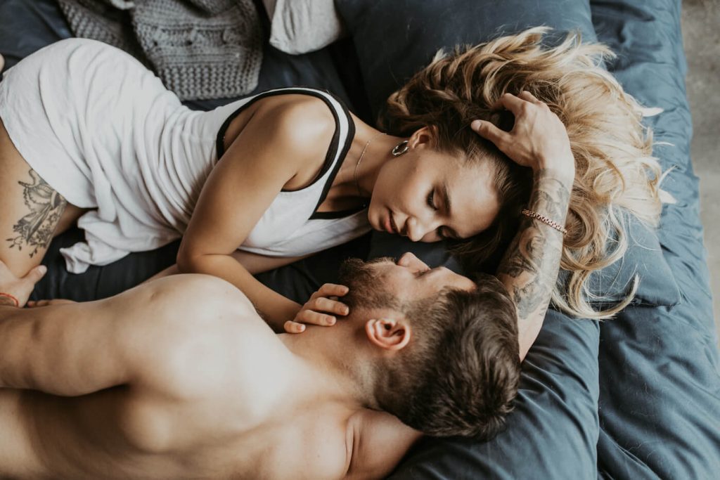 man and woman in loving embrace laid on the bed