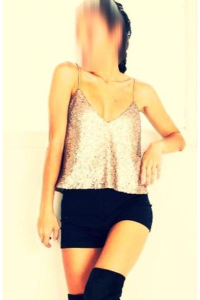 Independent Luton escort poses in silver shimmering vest and black hot pants