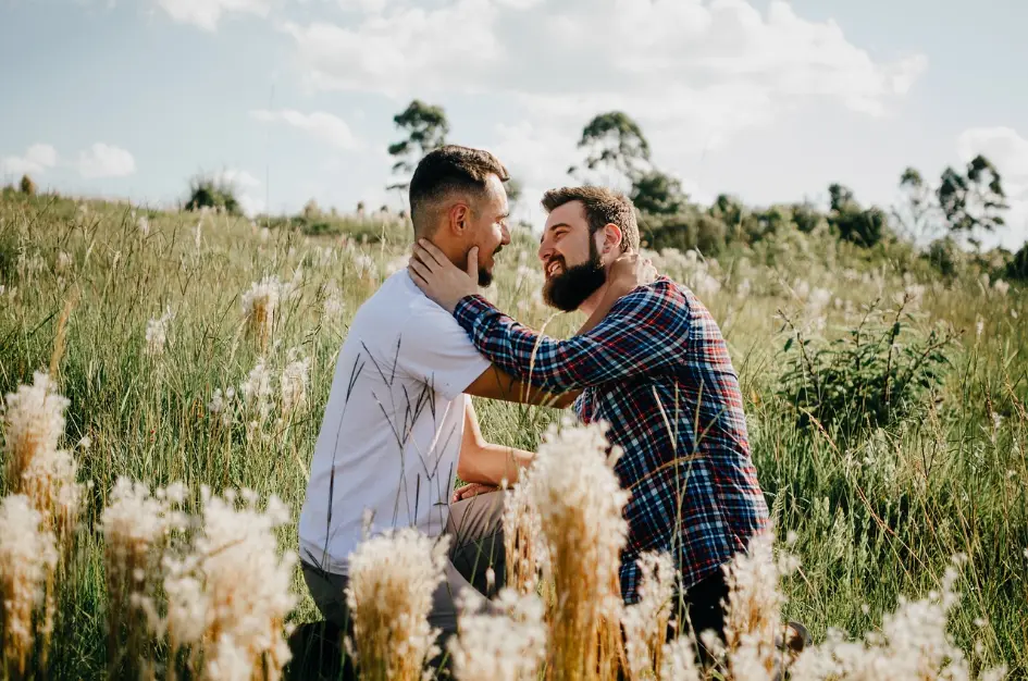 Two men kissing in a field