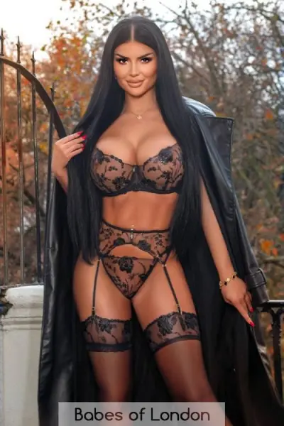 Super busty escort wearing a long leather coat and classy underwear